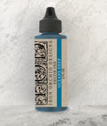 Bottle of Iron Orchid Designs decor ink with a textured white background