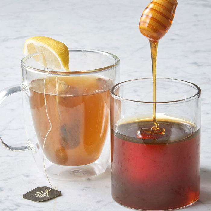 Honey Dipper Glass Jar next to tea cup with teabag and lemon wedge
