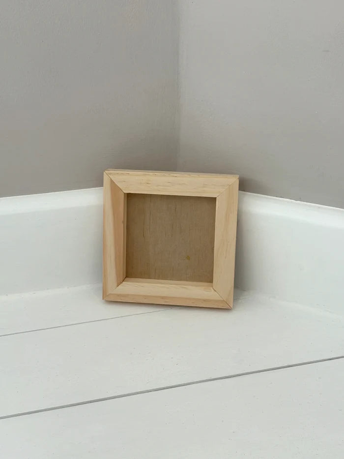Small wood frame on a white surface with a gray wall background