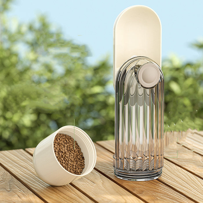 A well-lit photo of the Beige Portable Dog Water Bottle set down on a wooden patio with a dog bowl nearby