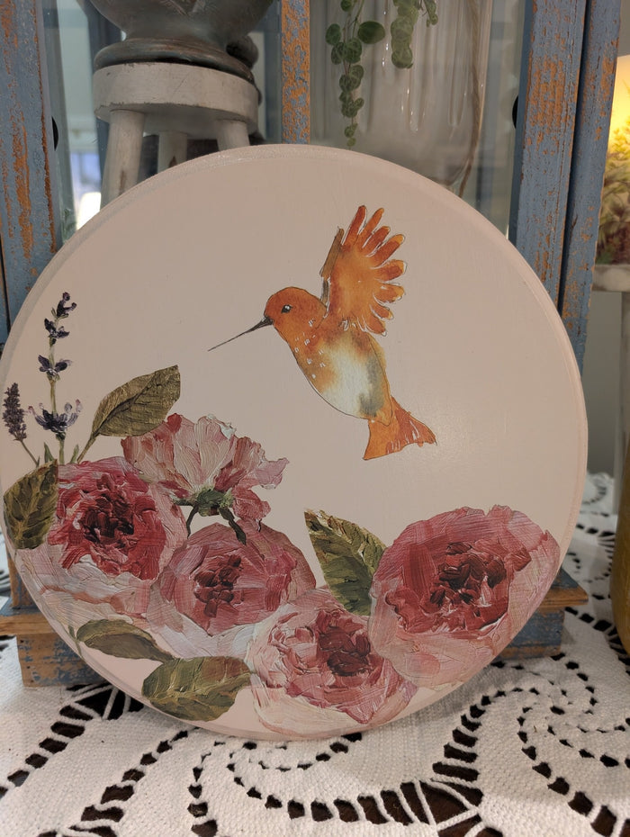 Decorative plate with a hummingbird and floral design on a doily.